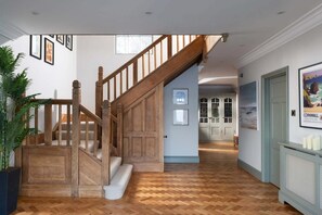 Eine Holztreppe führt zu einer Zwischenebene mit einem Fischgrätparkett.