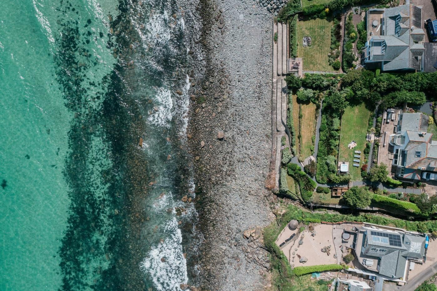Une propriété située sur la côte, avec un rivage rocheux, une piscine et un jardin bien entretenu.