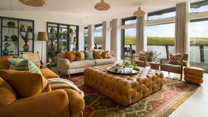 A spacious living room with a large window, a sofa set, a coffee table, and a rug. - 4 Bed in Watergate Bay (oc-b584345) (Tregurrian)