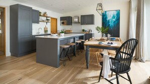 Uma cozinha moderna com uma ilha central, banquetas de bar e uma mesa de jantar com cadeiras.