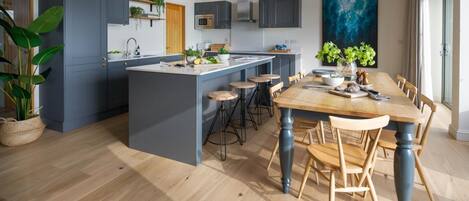 Una cocina moderna con una isla central, taburetes de bar y una mesa de comedor con sillas.
