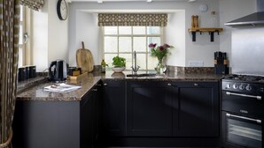 A modern kitchen with black cabinets, a granite countertop, a stove, and a window with a view. - 5 Bed in Porth (oc-b584392) (Newquay)