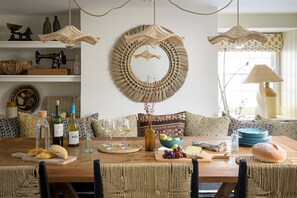 A dining area with a wooden table, woven chairs, and a woven wall hanging. - 5 Bed in Porth (oc-b584392) (Newquay)