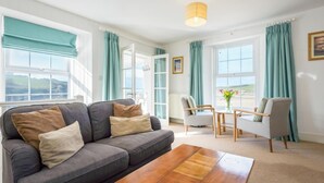 A living room with a sofa, a coffee table, a chair, and a view of the outdoors. - 2 Bed in Porth (oc-b584410) (Newquay)