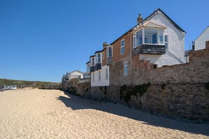 Ein Küstengebäude mit einer Steinsäule, einem Sandstrand und blauem Himmel.