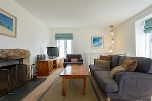 Una sala de estar con sofá, una mesa de centro, televisor y chimenea.