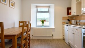 A kitchen with a window, a dining table with chairs, and a radiator. - 2 Bed in Porth (oc-b584410) (Newquay)