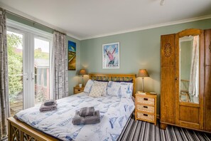 Ein Schlafzimmer mit einem Bett, Nachttischen, einem Kleiderschrank und einem Fenster mit Vorhängen.