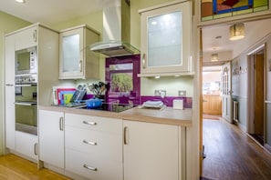 A kitchen with white cabinets, a built-in oven, and a purple backsplash. - 3 Bed in Southwold (oc-hseami) (Southwold)