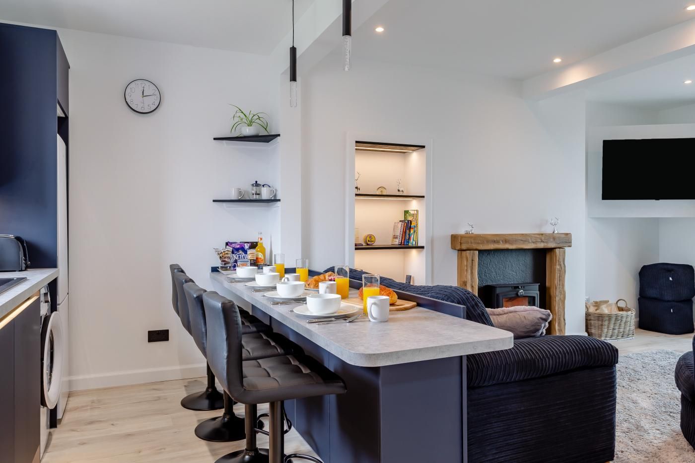 Une cuisine moderne avec un coin repas, une horloge et une cheminée.