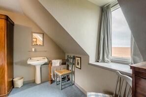 A small, cozy room with a sloped ceiling, a window with curtains, a wooden chair, a small table, and a cabinet. - 2 Bed in Dunbar (oc-t42811) (Innerwick)