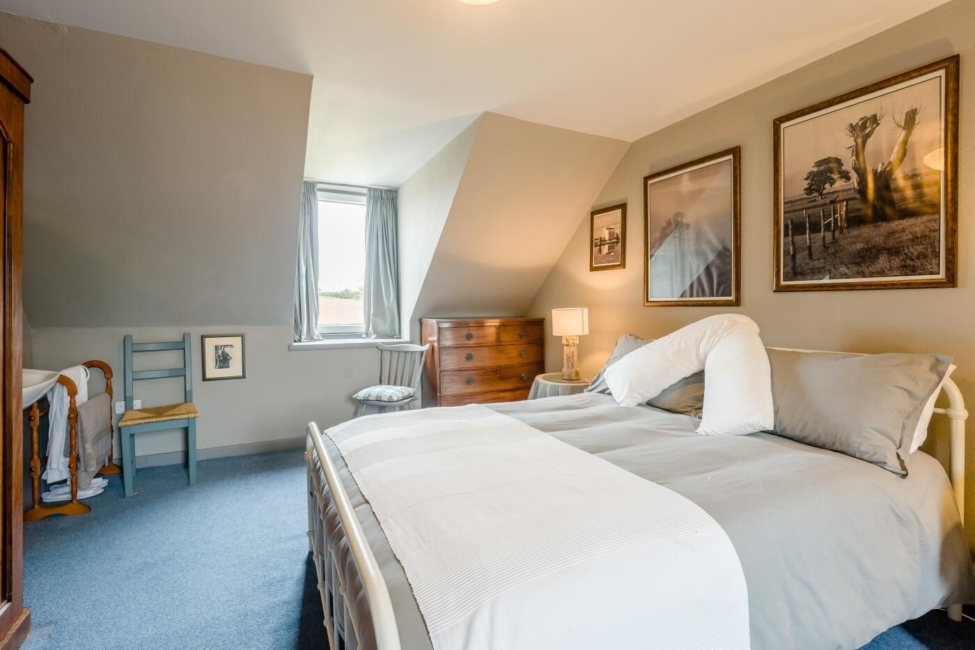 A bedroom with a large bed, a dresser, a chair, and a window.