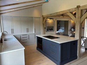 A modern kitchen with white cabinets, a central island, and a built-in oven. - 2 Bed in Crundale (oc-c45424) (Crundale)