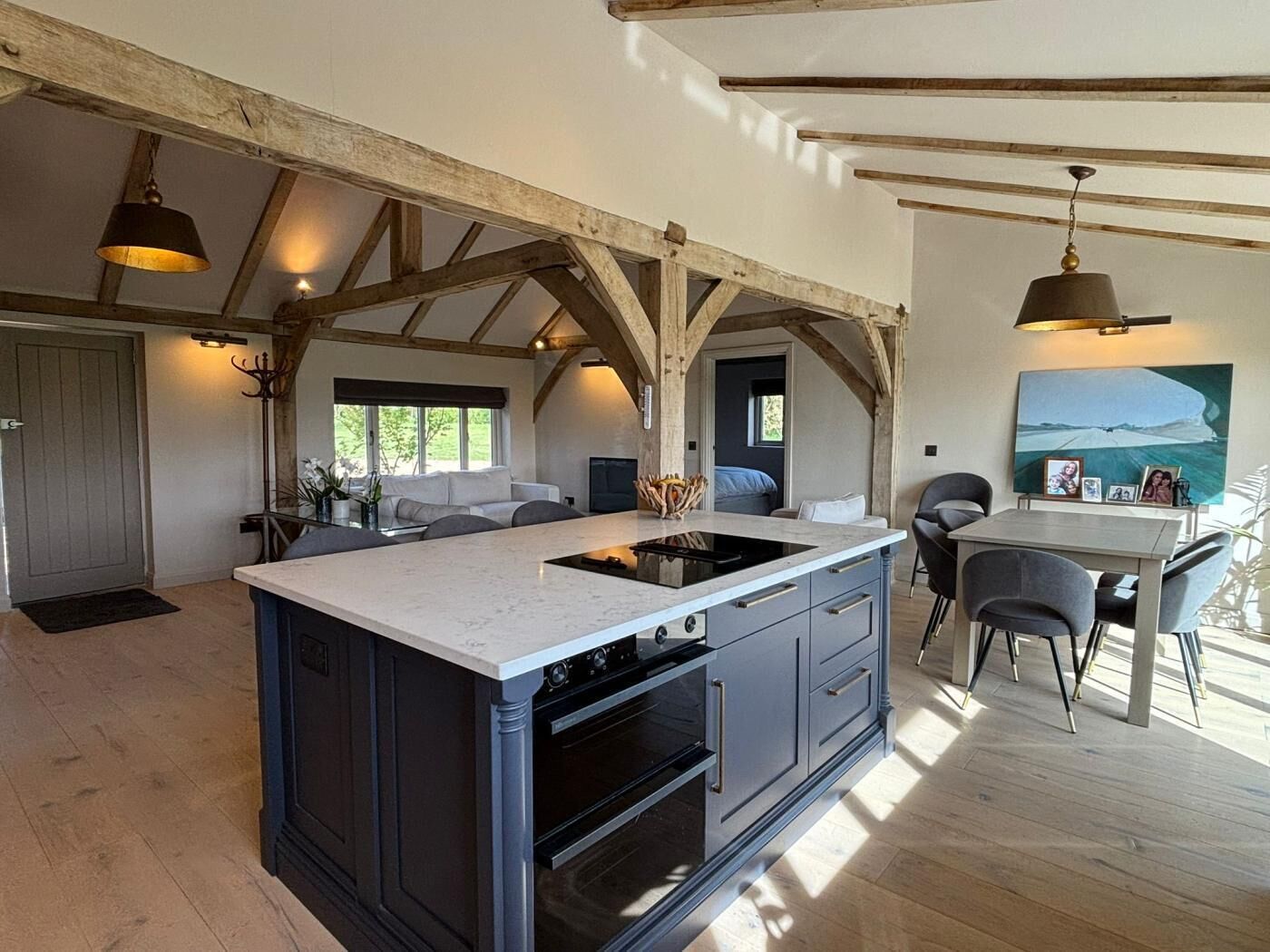 A spacious kitchen with a large island, wooden beams, and pendant lighting.