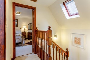 A staircase with wooden balusters leading to a bedroom with a bed, dresser, and lamp. - 2 Bed in Ballater (oc-o45326) (Ballater)