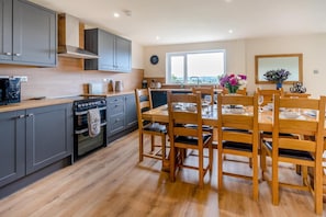 Una cocina moderna con armarios grises, una mesa de comedor de madera y vistas al exterior.