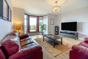 Ein modernes Wohnzimmer mit Ledersofa, Couchtisch, Flachbildfernseher und Bücherregal.