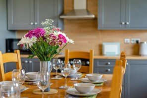 A dining table set with white plates, bowls, and wine glasses, with a vase of flowers in the center. - 4 Bed in Longforgan (oc-w42661) (Longforgan)
