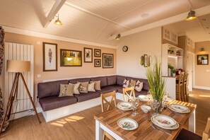 A cozy living room with a sofa, dining table set for four, and a kitchen in the background. - 2 Bed in Wichenford (oc-t45441) (Ockeridge)