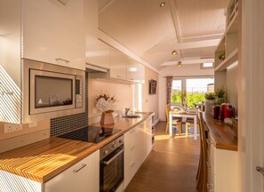 A modern kitchen with a wooden countertop, built-in oven, and a dining area with a view of greenery.