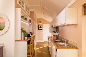A modern kitchen with white cabinets, wooden countertops, and a built-in oven. There is a dining area with a table and chairs, and a potted plant on the counter. - 2 Bed in Wichenford (oc-t45441) (Ockeridge)