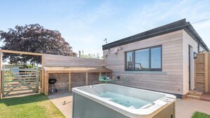 Uma casa moderna com hidromassagem, um alpendre coberto e uma cerca de madeira.
