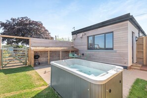 Ein modernes Haus mit Whirlpool, überdachter Terrasse und Holzzaun.