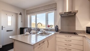 Uma cozinha moderna com ilha central, eletrodomésticos de aço inoxidável e vista para o exterior.