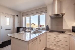 Eine moderne Küche mit einer Kochinsel, Edelstahlgeräten und Blick ins Freie.