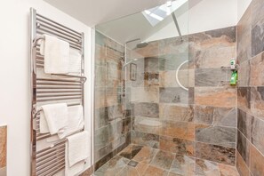 Eine Dusche mit Glastür, ein Handtuchhalter mit mehreren Handtüchern und ein Duschkopf.