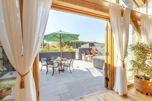 Eine offene Terrasse mit Tisch und Stühlen, einem grünen Sonnenschirm und einem Blumentopf.
