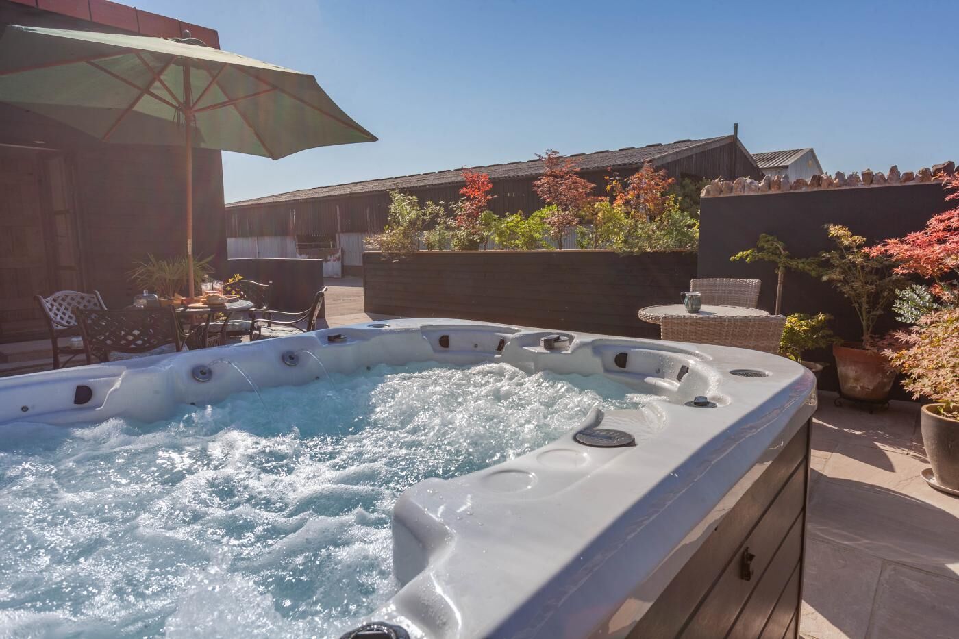 Ein Whirlpool mit Holzterrasse und Gartenmöbeln.