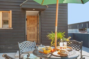 Un espace extérieur aménagé pour prendre les repas, avec une table, des chaises et un parasol.