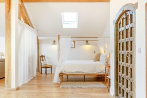 A bedroom with a wooden bed, a chair, a bedside table, a window, and a door with a metal grid. - 1 Bed in Langford (oc-p45260) (Langford)