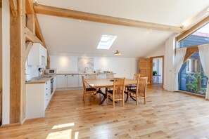 A spacious kitchen with a dining area, wooden beams, and a skylight. - 1 Bed in Langford (oc-p45260) (Langford)