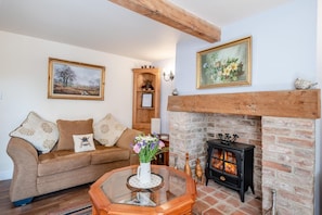 A cozy living room with a sofa, a glass coffee table, a fireplace, and a wooden cabinet. - 2 Bed in Tetford (oc-g45404) (Tetford)
