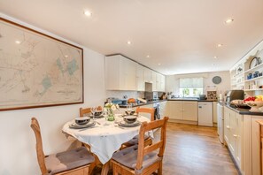 A modern kitchen with white cabinets, a dining table set for four, and a map on the wall. - 2 Bed in Tetford (oc-g45404) (Tetford)