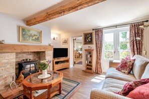 Ein gemütliches Wohnzimmer mit Kamin, Fernseher und einer Couch.