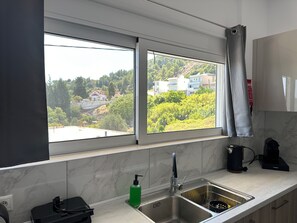 A kitchen with a large window, a sink, and a coffee machine. - Casa Platania – Private Mountain Retreat in Rhodes (Rhodes)