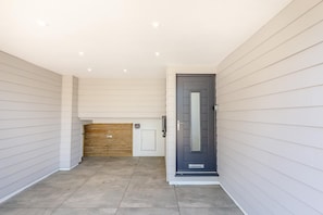 Ein aufgeräumter, moderner Eingangsbereich mit einer grauen Tür, einer Holztür zur Garage und einem gefliesten Boden.