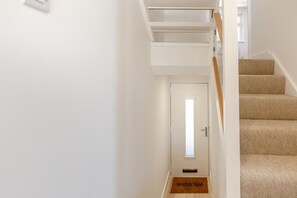 Eine Treppe mit Teppich und einer weißen Tür mit Fußmatte.