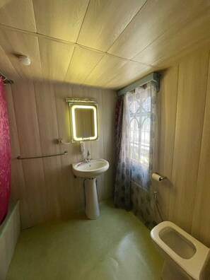 Um banheiro pequeno com pia suspensa, espelho iluminado, vaso sanitário e cortina de chuveiro.