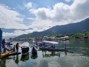 Um rio calmo com barcos e um cais, cercado por montanhas e um céu claro.