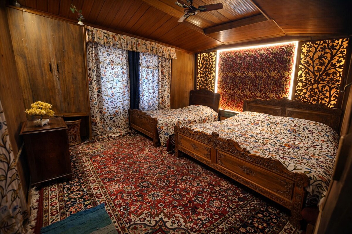 Quarto tradicional com duas camas de madeira, um tapete estampado e um painel decorativo na parede.