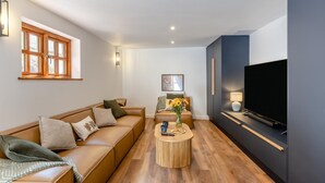 A modern living room with a sofa, coffee table, and a flat-screen TV. - 5 Bed in Bishops Lydeard (oc-b45427) (Triscombe)