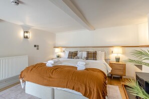 A hotel room with a bed, bedside lamps, a nightstand, a radiator, and a potted plant. - 5 Bed in Bishops Lydeard (oc-b45427) (Triscombe)