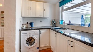 A compact kitchen with a washing machine, a sink, and a window with a view. - 2 Bed in Snettisham (oc-d45324) (Snettisham)
