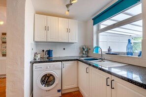A compact kitchen with a washing machine, a sink, and a window with a view. - 2 Bed in Snettisham (oc-d45324) (Snettisham)