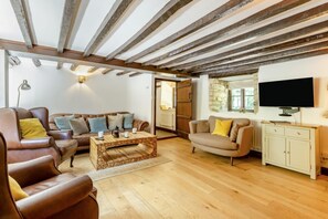 Ein Wohnzimmer mit Couchtisch aus Holz, Ledersofas, einem Fernseher und einer Steinwand.