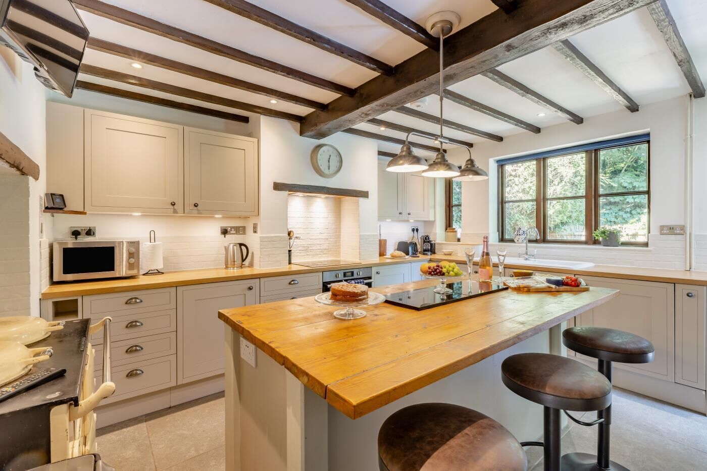 A modern kitchen with a wooden island, stainless steel appliances, and a large window providing natural light.